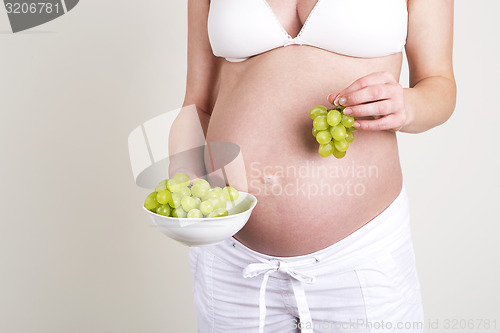 Image of Pregnant woman with a bowl of grapes in her hands