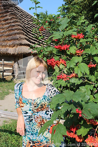 Image of girl with red guelder-rose besides an rural house