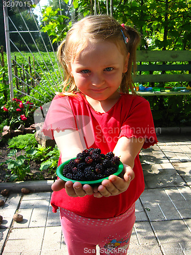 Image of girl offers the plate with ripe mulberry