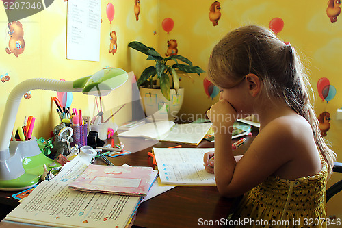 Image of schoolgirl learns lessons at the table