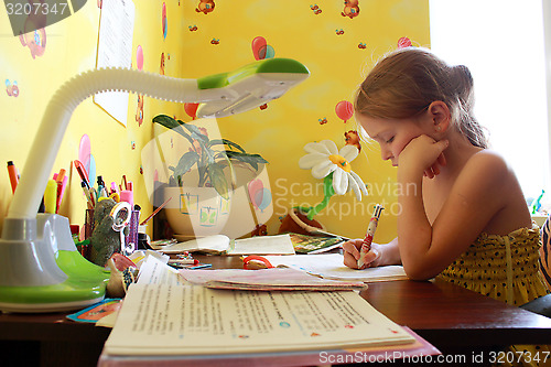 Image of schoolgirl learns lessons at the table