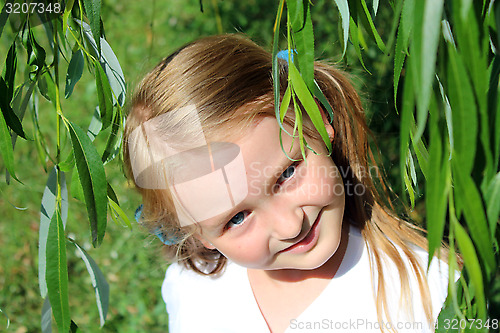 Image of girl smiling besides the leaves of willow
