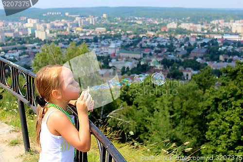 Image of little girl swelling soap bubbles out of city