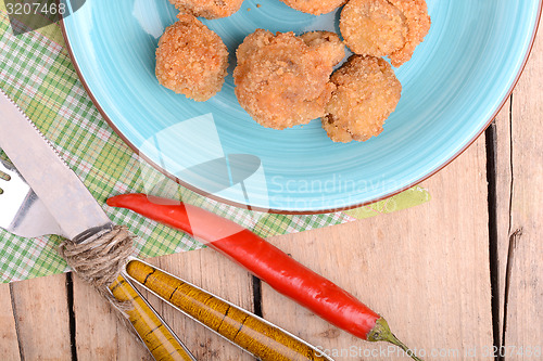 Image of meat chop on blue plate with red pepper