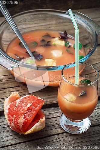 Image of fresh juice of tropical citrus fruits on wooden background