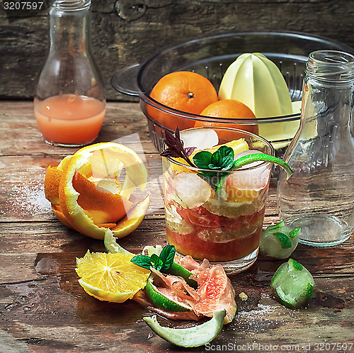 Image of fresh juice of tropical citrus fruits on wooden background