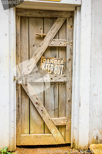 Image of old wooden door with danger sign