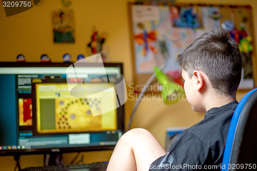 Image of Boy using computer at home, playing game