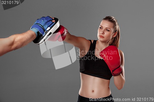 Image of beautiful woman is boxing on gray background