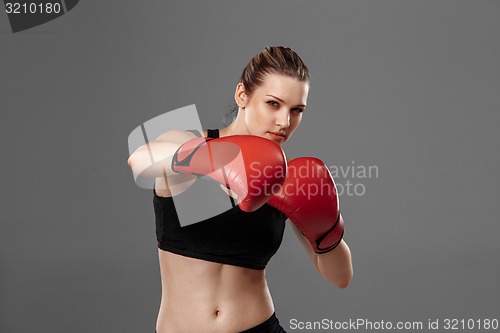 Image of beautiful woman is boxing on gray background