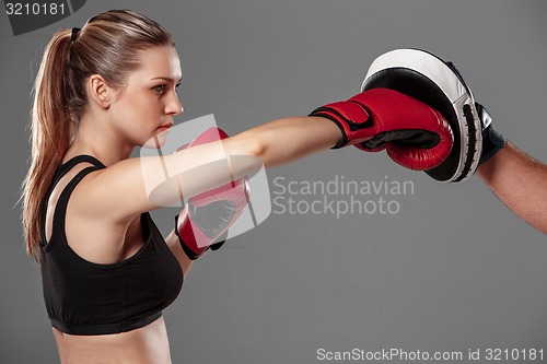 Image of beautiful woman is boxing on gray background