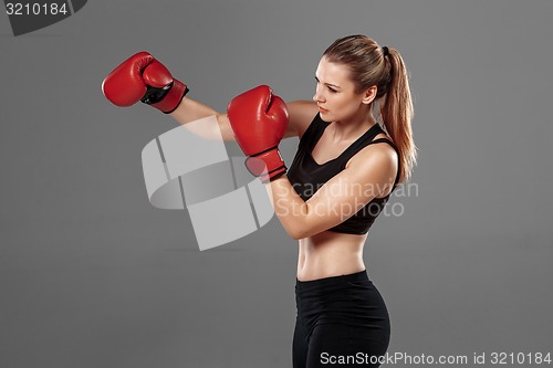Image of beautiful woman is boxing on gray background