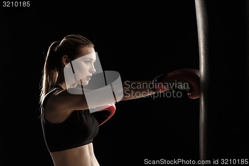 Image of beautiful woman is boxing on black background