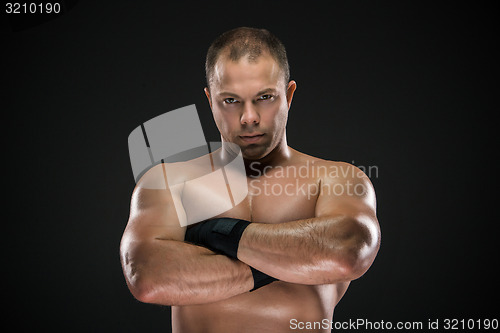 Image of studio portrait of young caucasian boxer with folded hands posing ark background