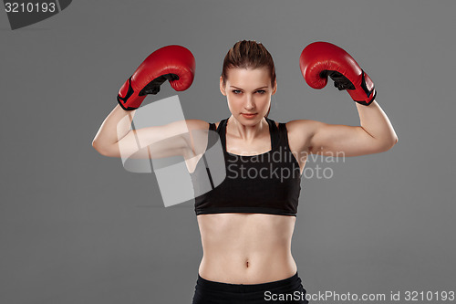 Image of Beautiful winner. Blond hair woman in red boxing gloves standing on gray background