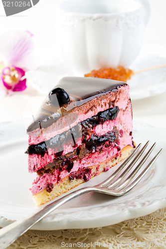 Image of Piece of cake with souffle and blackcurrant jelly on a white pla