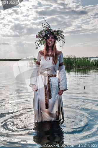 Image of Beautiful woman with flower wreath stands in water