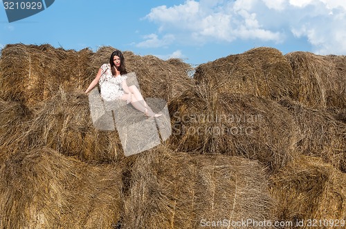 Image of Young beautiful woman relaxes on hay