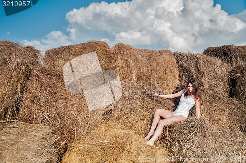 Image of Young pretty woman relaxes on hay