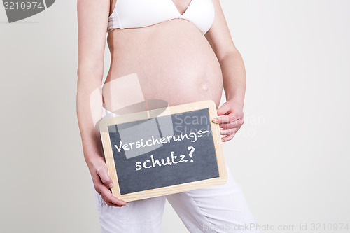Image of Pregnant woman with German word insurance cover on blackboard
