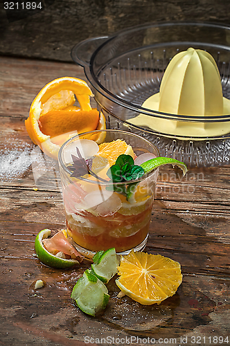 Image of fresh juice of tropical citrus fruits on wooden background