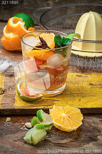 Image of fresh juice of tropical citrus fruits on wooden background