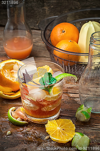 Image of fresh juice of tropical citrus fruits on wooden background