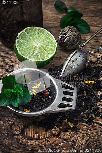 Image of tea brew with lime and mint on wooden background 