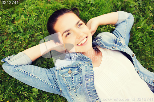 Image of smiling young girl lying on grass