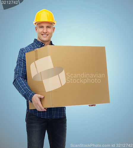 Image of smiling male builder in helmet with cardboard box