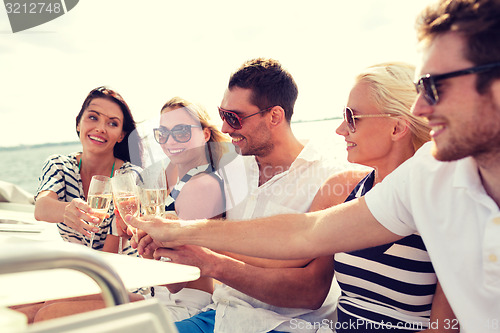 Image of smiling friends with glasses of champagne on yacht