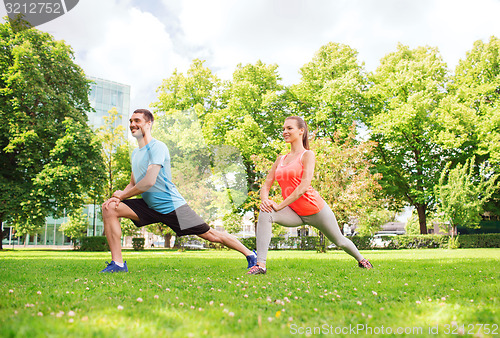 Image of smiling couple stretching outdoors