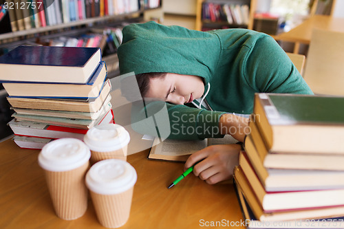 Image of tired student or man with books in library