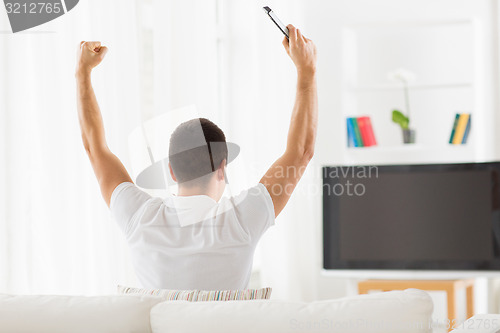 Image of man watching tv and supporting team at home