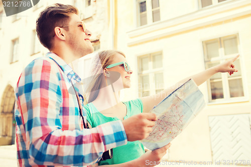 Image of smiling couple with map and photo camera in city