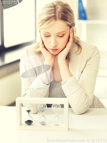 Image of pensive businesswoman with sand glass