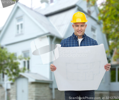 Image of smiling builder with blueprint over house
