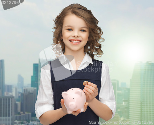 Image of happy girl holding piggy bank and coin