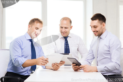 Image of three smiling businessmen with tablet pc in office