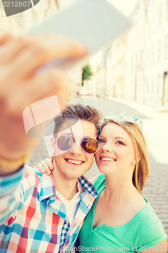 Image of smiling couple with smartphone in city