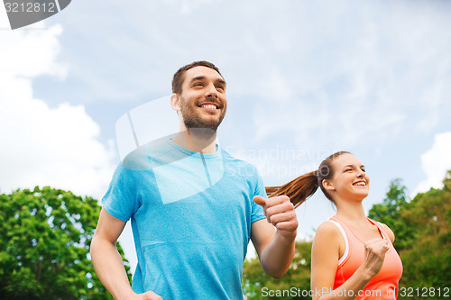 Image of smiling couple running outdoors