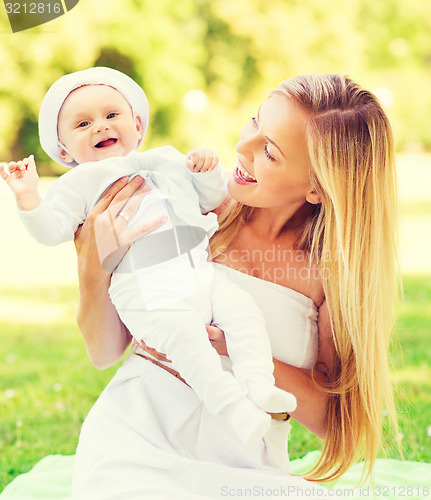 Image of happy mother with little baby sitting on blanket