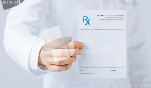 Image of male doctor holding rx paper in hand