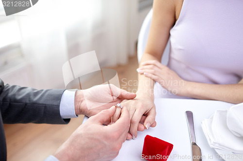 Image of close up of man putting ring to his fiance finger