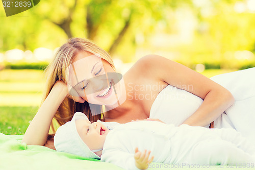 Image of happy mother lying with little baby on blanket