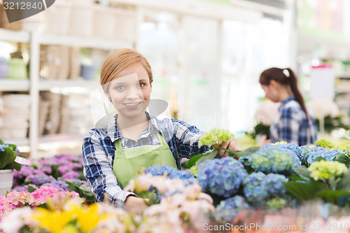 Image of happy woman taking care of flowers in greenhouse