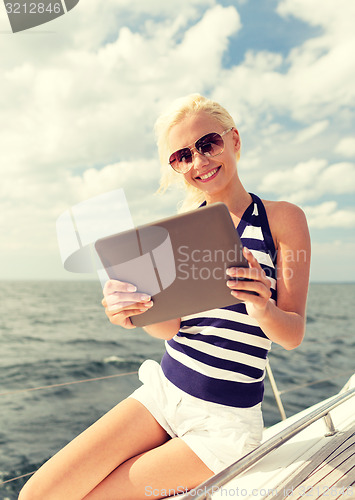 Image of smiling woman sitting on yacht with tablet pc