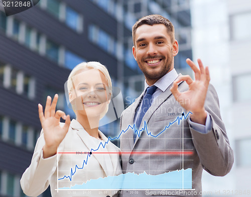 Image of smiling businessmen standing over office building