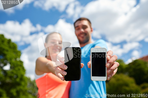 Image of two smiling people with smartphones outdoors