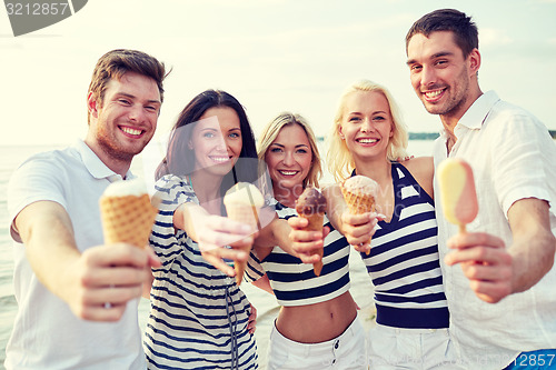 Image of smiling friends eating ice cream on beach